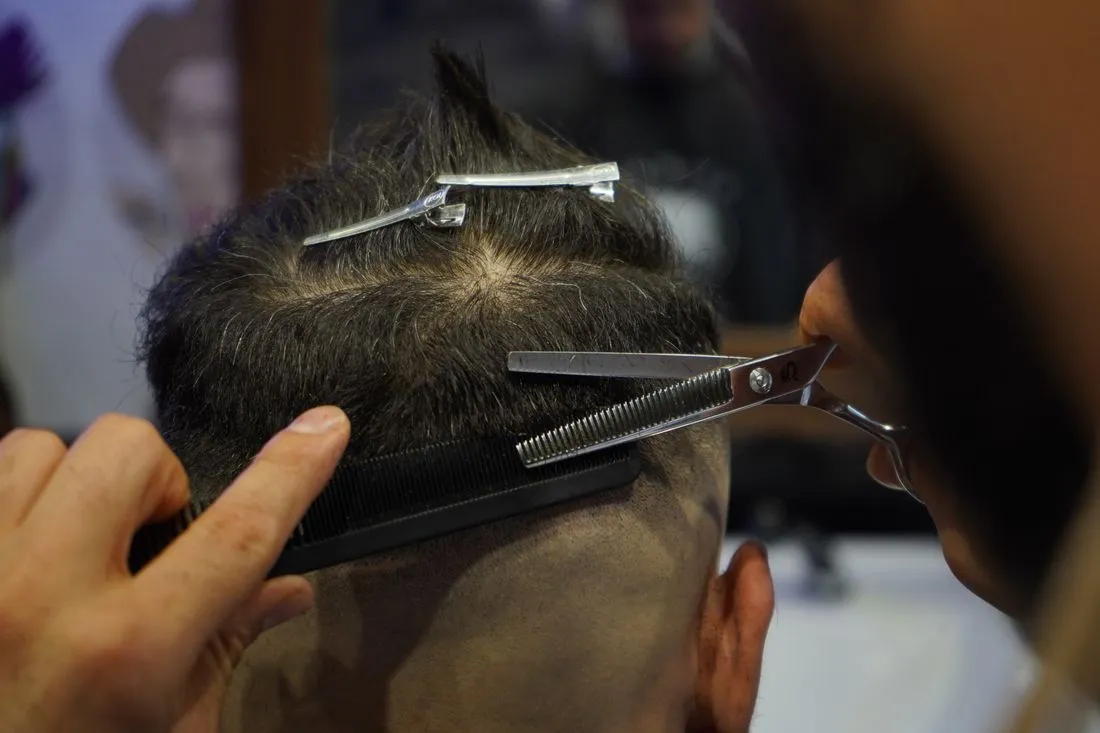 Barbero cortando el cabello a un cliente con tijeras