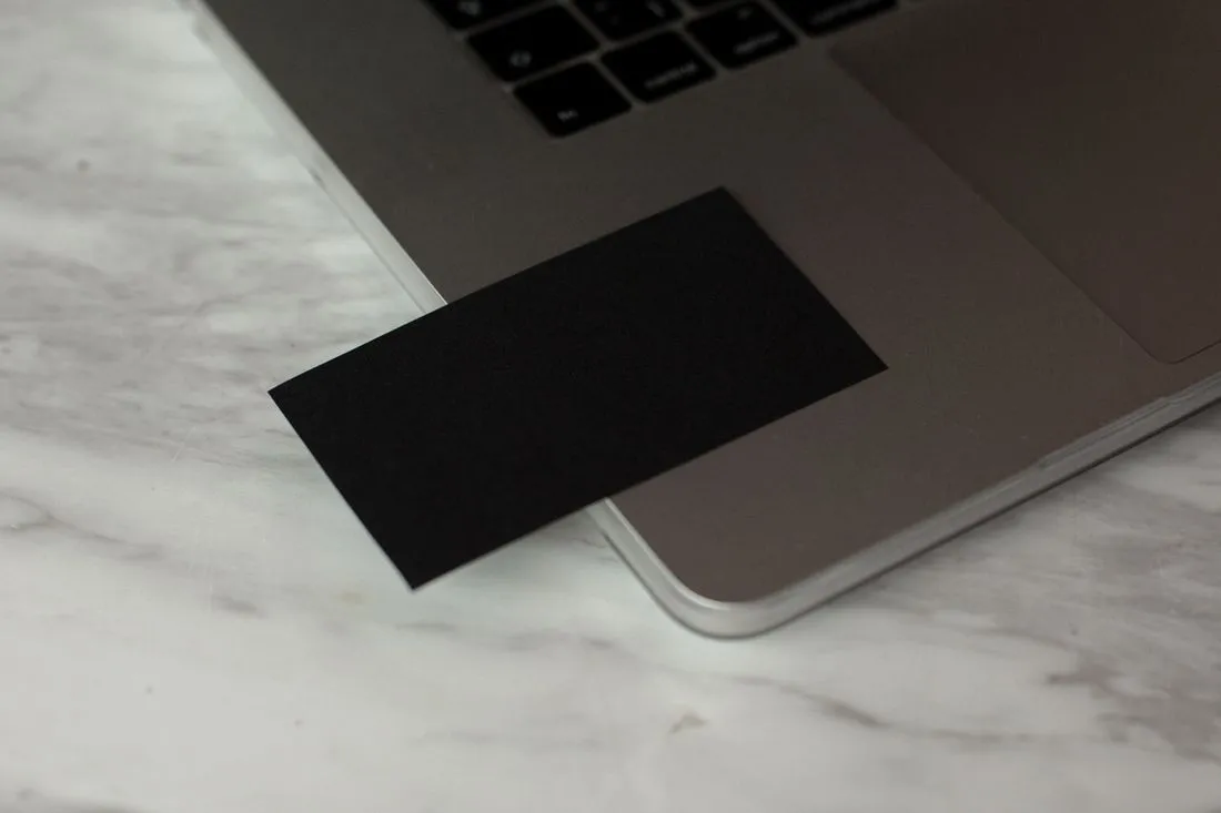 Tarjeta de presentación negra en blanco, lista para imprimir, sobre una laptop