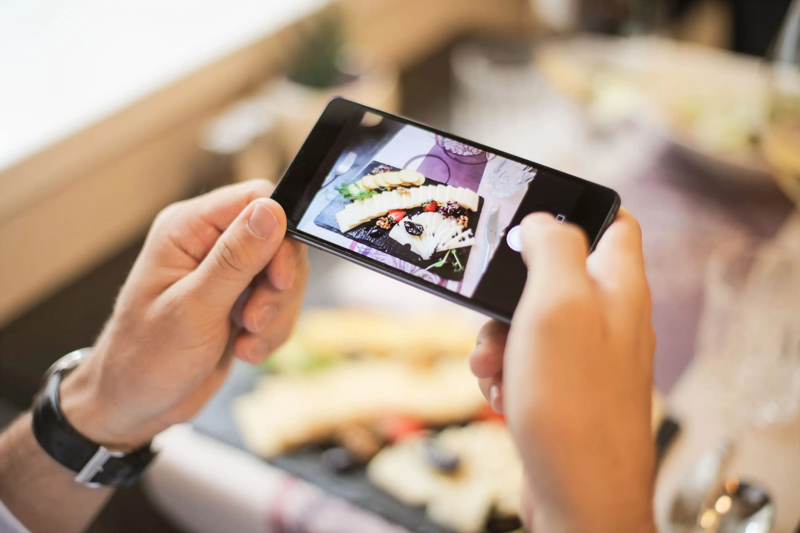 Manos fotografiando un platillo con el teléfono para una publicación