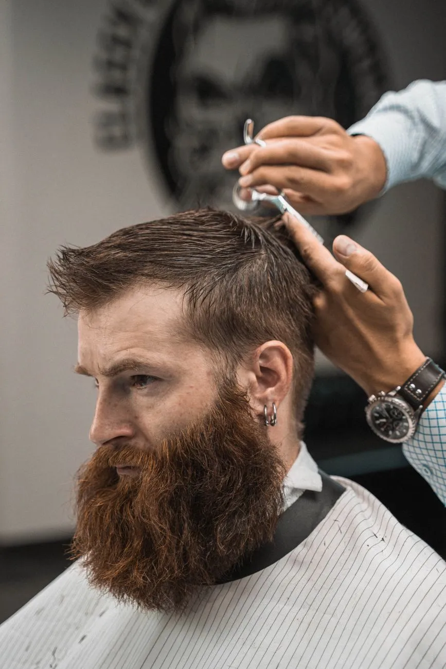 Barbero arreglando el corte y la barba de un cliente