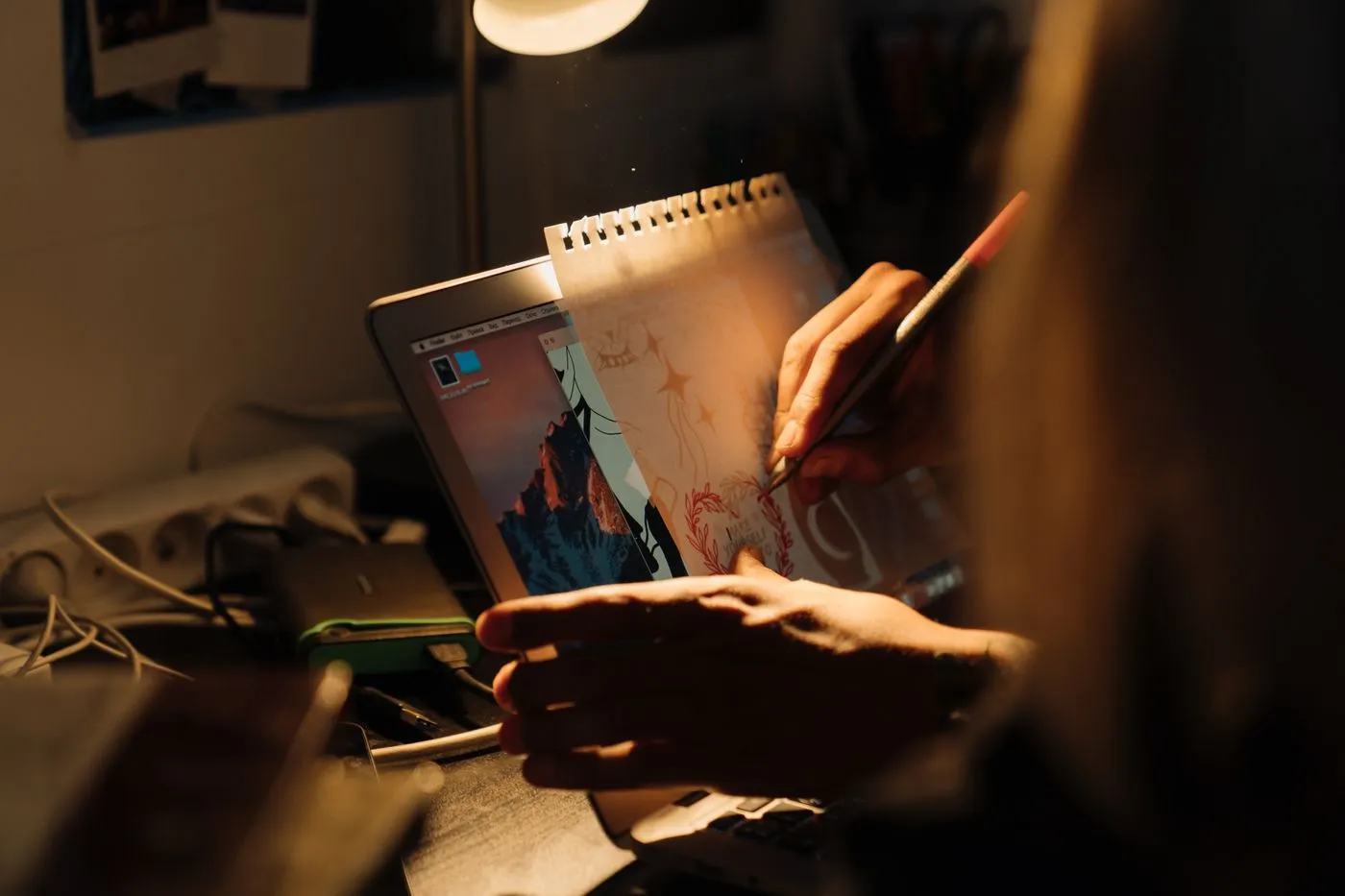 Persona dibujando bocetos de un sitio web sobre papel, con luz cálida
